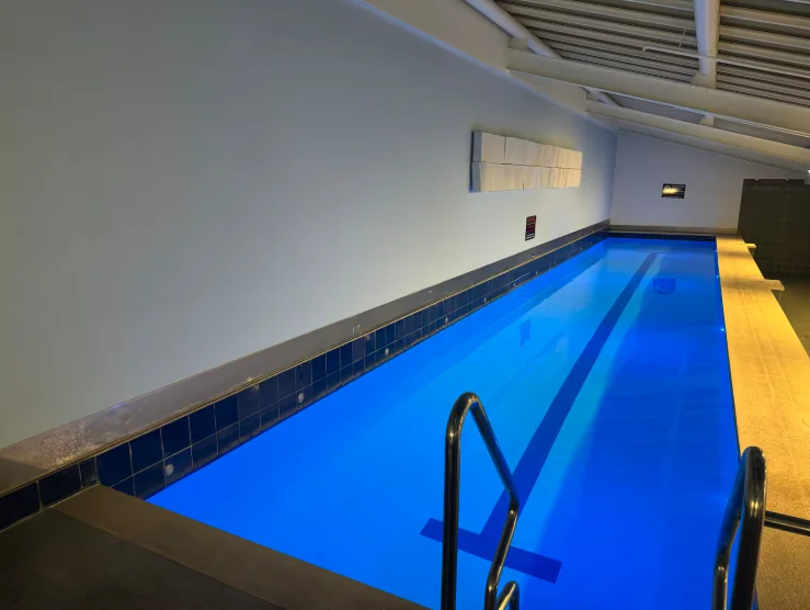 A long indoor lap pool lit bright blue, with a steel ladder at the near end, in one of our buildings